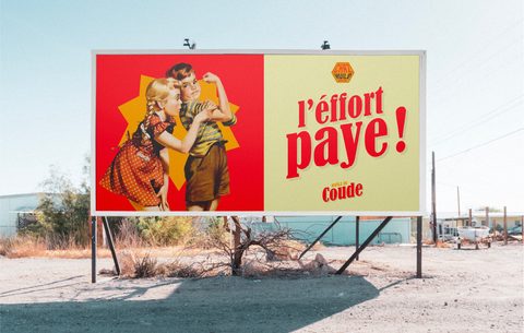 Panneau publicitaire Huile de Coude « L’effort paye ! » au bord d’une route dans le désert.