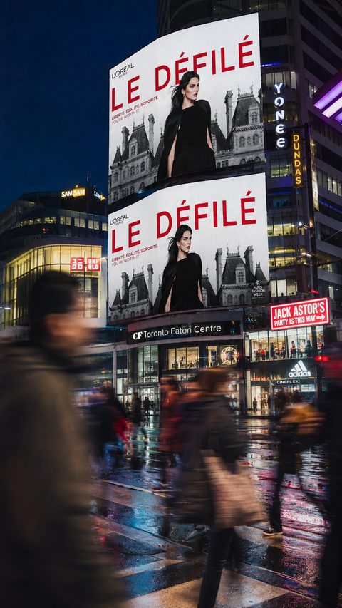Écrans géants de Yonge-Dundas Square à Toronto affichant la campagne Le Défilé, de nuit.
