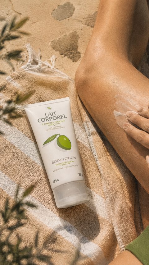 Tube de lait corps Une Olive en Provence tenu contre une épaule.